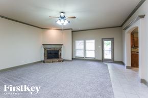 Burleson house for rent - A spacious room with a fireplace and a ceiling fan.