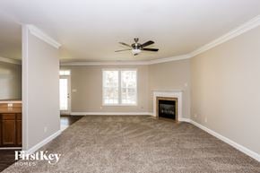 Charlotte house for rent - A spacious living room with a fireplace and a ceiling fan.
