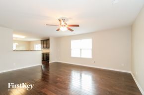 Whitsett house for rent - A spacious room with a ceiling fan and hardwood floors.