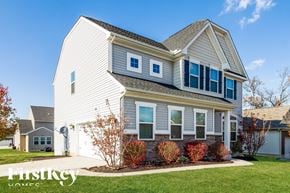 Morrow house for rent - A house with a white garage door and a red bush in front.