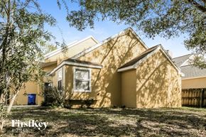 Oviedo house for rent - the front of a yellow house with a yard and trees