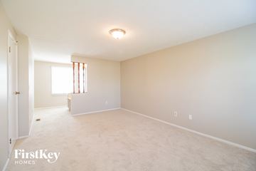 Batavia house for rent - a spacious living room with white carpet and white walls and a window