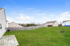 Winston Salem house for rent - A grassy backyard with a fence and houses in the background.
