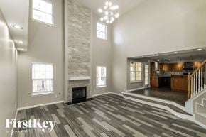 Dacula house for rent - A spacious living room with a stone fireplace and a staircase leading to the upper floor.