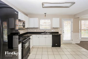 Mooresville house for rent - A kitchen with black appliances and white cabinets.