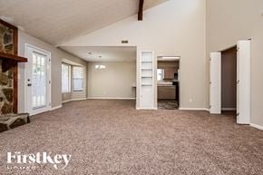 Jonesboro house for rent - A spacious room with a carpeted floor and a stone fireplace on the left side.