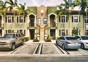 Homestead apartment for rent - A silver truck is parked in front of a two-story building with a balcony.