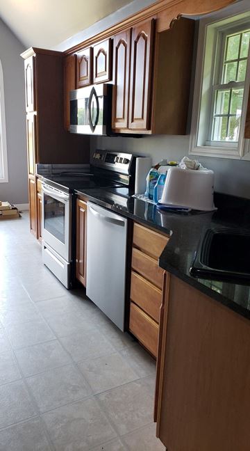 Girdletree house for rent - A kitchen with wooden cabinets and black countertops.