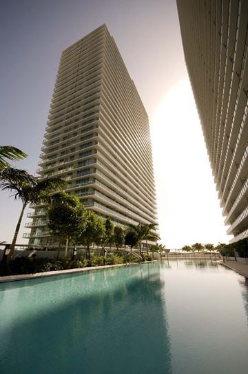 Miami apartment for rent - a large swimming pool in front of a tall building