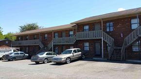 Winston Salem apartment for rent - a parking lot in front of a brick building with cars parked