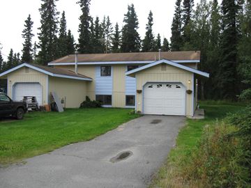 Kenai apartment for rent - A house with a garage and a car parked in front.