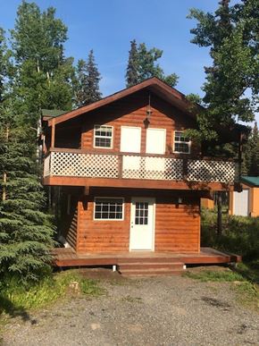 Kasilof house for rent - a wooden house with a balcony and trees