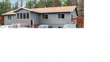Soldotna apartment for rent - A grey house with a red fence and cars parked in front.