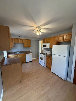 Cincinnati apartment for rent - A kitchen with wooden cabinets and white appliances.