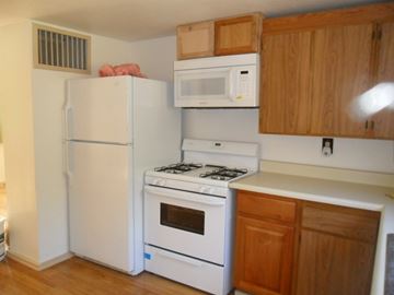 Kenai apartment for rent - A white refrigerator and oven in a kitchen with wooden cabinets.