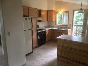 Soldotna apartment for rent - an empty kitchen with wooden cabinets and a white refrigerator