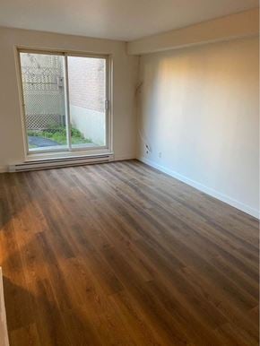 Brossard apartment for rent - an empty living room with wood floors and a window