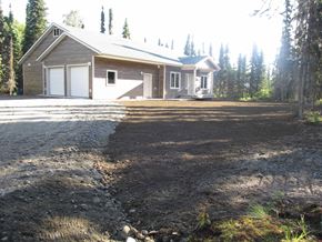 Soldotna apartment for rent - A house with a garage is situated in a wooded area.