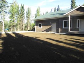 Soldotna apartment for rent - A house with a green roof is surrounded by trees.