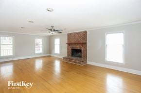 Charlotte house for rent - a living room with a brick fireplace and wooden floors and a ceiling fan