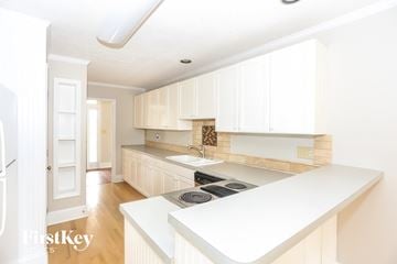 Charlotte house for rent - a kitchen with white cabinets and a stove and a sink