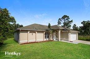 Lehigh Acres house for rent - a beige house with a lawn and a garage