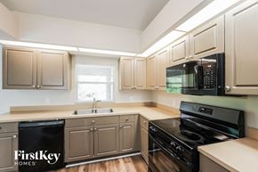 Lehigh Acres house for rent - a kitchen with white cabinets and black appliances