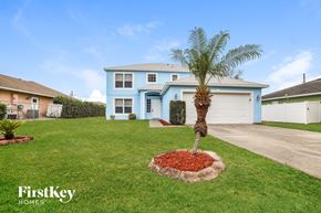 Poinciana house for rent - a palm tree in a yard in front of a blue house