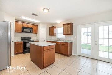 Poinciana house for rent - a kitchen with wooden cabinets and a door to a yard