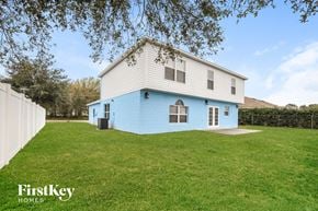 Poinciana house for rent - a blue and white house with a grassy yard and a white fence