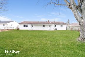 Trenton house for rent - A white house with a brown roof is surrounded by a grassy lawn.