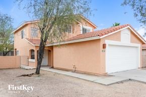 Tucson house for rent - a pink house with a white garage door and a tree