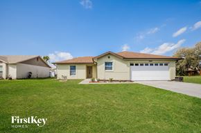 Poinciana house for rent - a beige house with a lawn and a white garage door