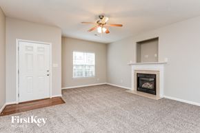Fuquay-Varina house for rent - A spacious living room with a fireplace and a ceiling fan.