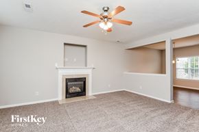 Fuquay-Varina house for rent - A living room with a fireplace and a ceiling fan.