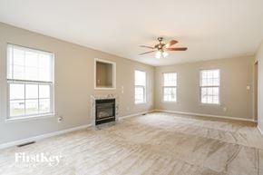 Durham house for rent - A spacious room with a fireplace and a ceiling fan.