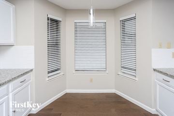 Mesquite house for rent - a kitchen with white cabinets and windows and a wood floor