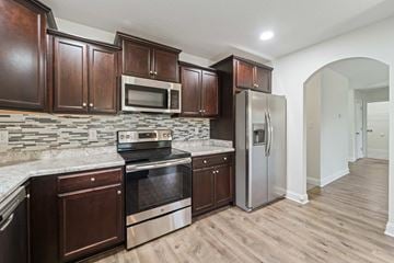 Sneads Ferry house for rent - A kitchen with wooden cabinets and a stone backsplash.