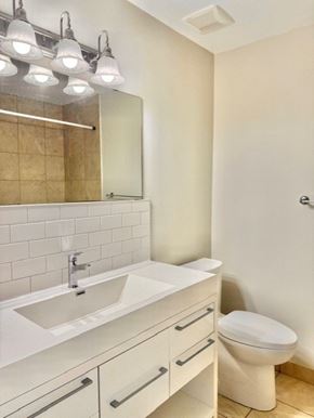 Guelph apartment for rent - A white bathroom with a sink, toilet and mirror.