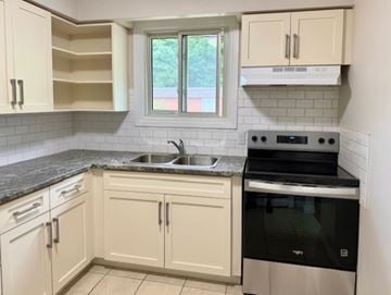 Guelph apartment for rent - A kitchen with white cabinets and a black oven.