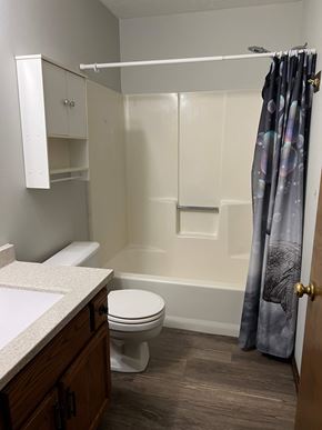 Hartville apartment for rent - A white toilet sits in a bathroom with a white tub and a shower curtain.