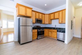 Berkeley apartment for rent - A kitchen with wooden cabinets, a refrigerator, and living room.