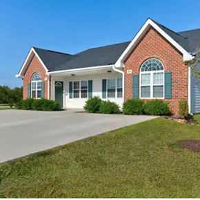 Youngsville apartment for rent - A red brick house with green shutters and a white garage door.