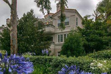 San Diego apartment for rent - A house with a balcony is surrounded by trees and bushes.