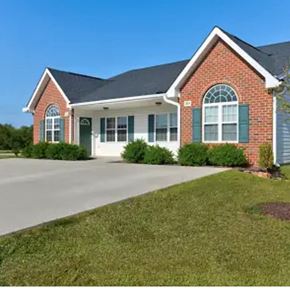 Youngsville apartment for rent - A brick house with green shutters and a white garage door.