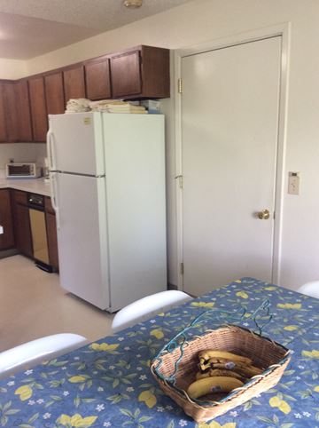Kenai house for rent - A kitchen with a white fridge and a table with a basket of bananas on it.