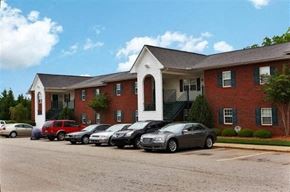Youngsville apartment for rent - A parking lot with cars and a red brick building with a white trim.