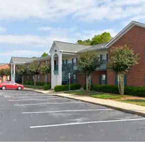 Youngsville apartment for rent - A red car is parked in a parking lot in front of a building.