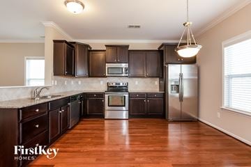 Mooresville house for rent - A kitchen with dark brown cabinets and a wooden floor.