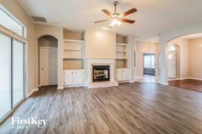Orange Park house for rent - A spacious living room with a fireplace and a ceiling fan.